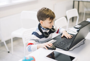little-boy-using-laptop-on-desk-in-the-classroom
